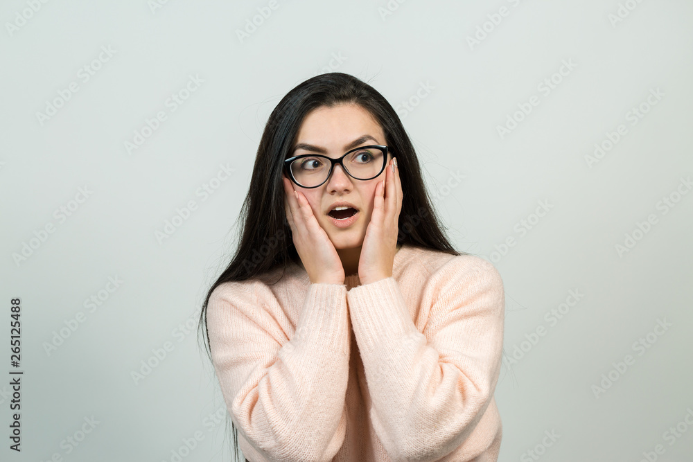A girl in the pink jumper holds her head. Concerned girl looks cautiously to the side, feeling pressured and perplexed. A girl in the pink jumper holds her head. Concerned girl looks cautiously to the side, feeling pressured and perplexed.
