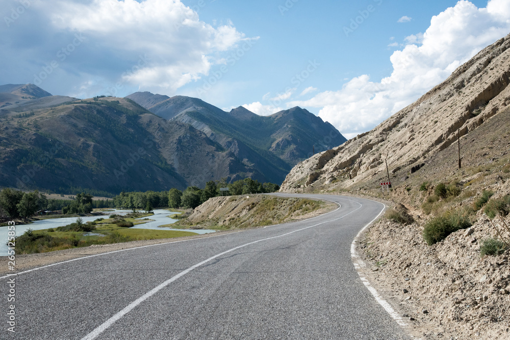 Asphalt winding road in the mountainous area Altai in the summer and sky with clouds