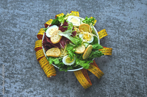 Healthy salad and measuring tape. The concept of losing weight on proper nutrition.