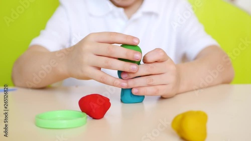 A child having fun at the table, close-up, playing in the colorful modeling of clay or dough for games photo