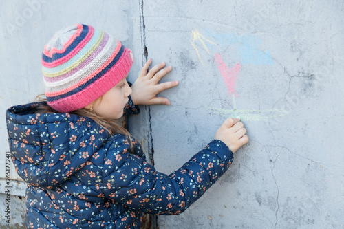 Girl draws with chalk on the concrete wall