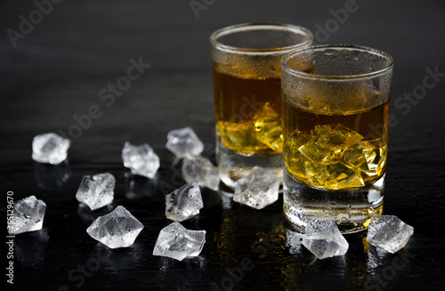 Two glass of whiskey with ice on wooden table. Copy space for text.