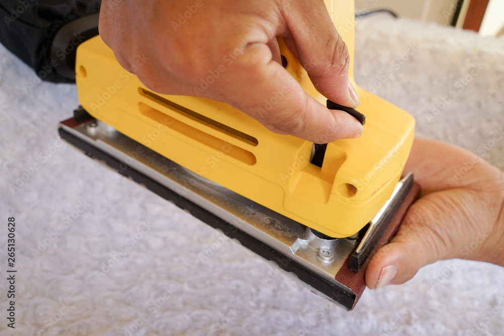 Put a sandpaper on electrical sanding machine or sander. woodworking