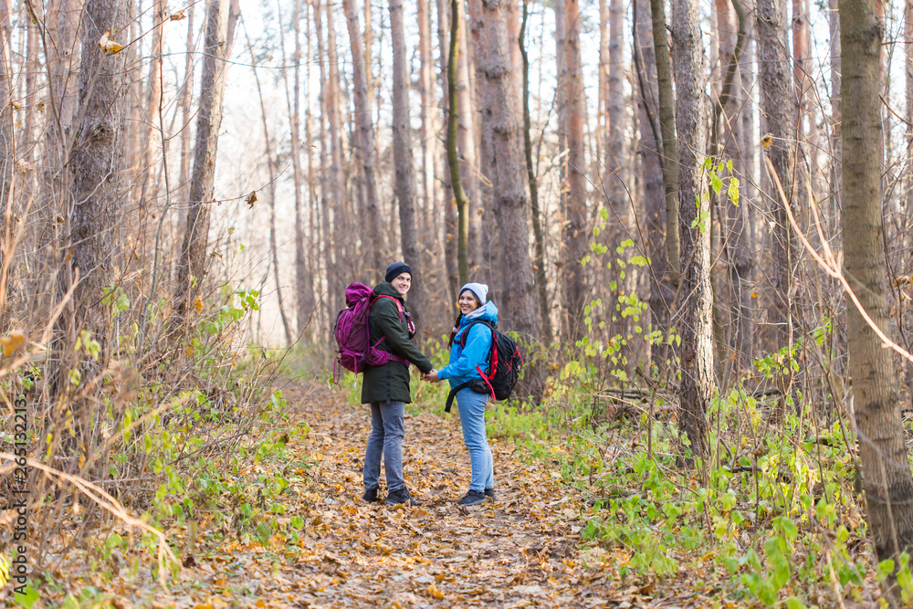 Travel, tourism, hike and nature concept - Tourists walking in park with backpack dressed in blue and black jackets Travel, tourism, hike and nature concept - Tourists walking in park with backpack dressed in blue and black jackets