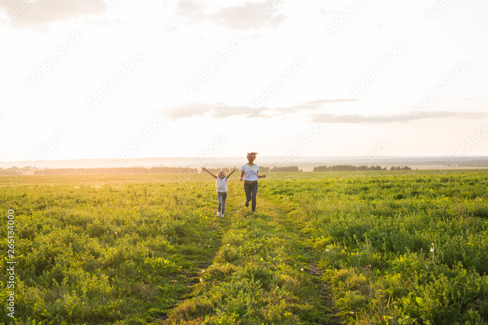 Family, summer and holiday concept - little daughter and mother run in the summer field