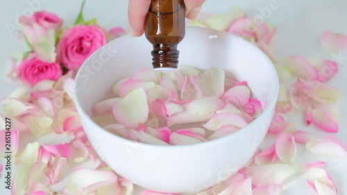 girl dripping aroma oil in a container with rose petals