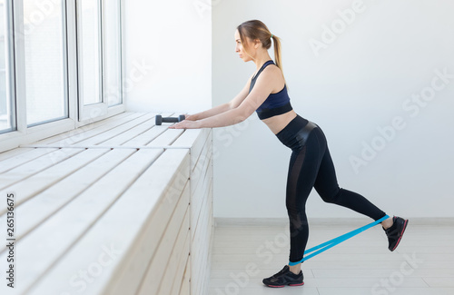 People, healthy and sport concept - Fit woman In sports clothes squatting with band