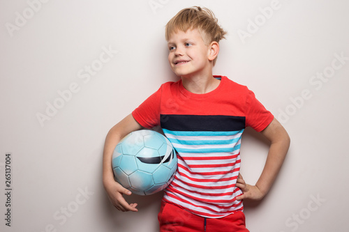 Cute little boy standing with soccer ball and looking at camera. Isolated on white. Studio portrait