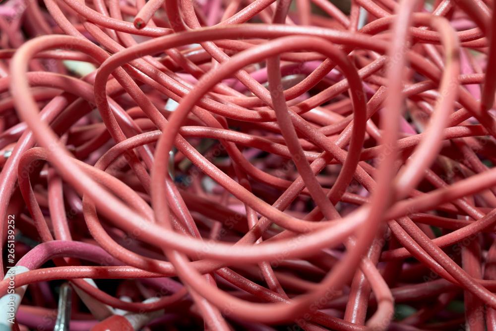 A large pile of highly entangled red electrical wires. Mess, chaos, confusion. A lot of twisted and curved cables.
