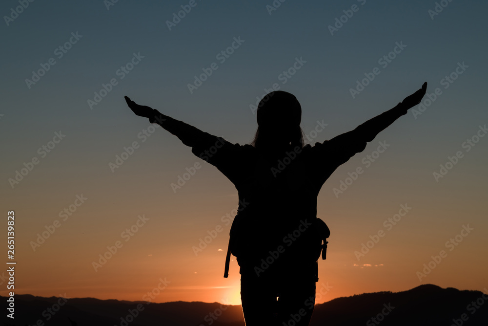 The silhouette of a young womanl on the mountain at sunset