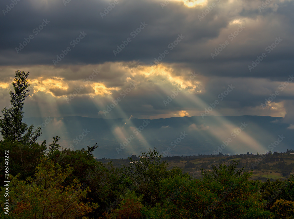 Multiple exposure of sunbeams casting their light over the valley at the Andean mountains of central Colombia.