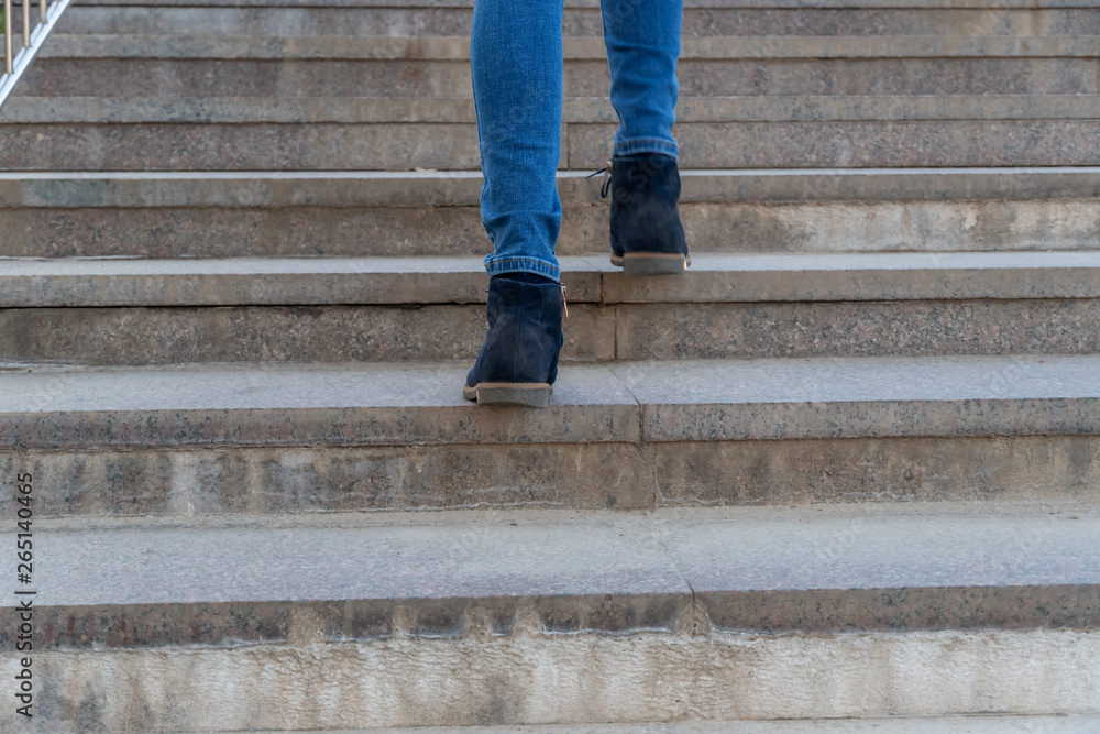 Closeup of legs of a woman in jeans and blue shoes walking upstairs Closeup of legs of a woman in jeans and blue shoes walking upstairs