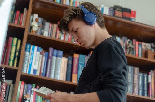 The teenage listens to music and reads book