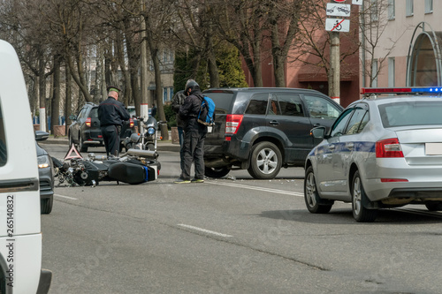 Accident in the city: a broken motorcycle and a car. Registration of a traffic accident. Traffic jam due to an accident, police car, police, people