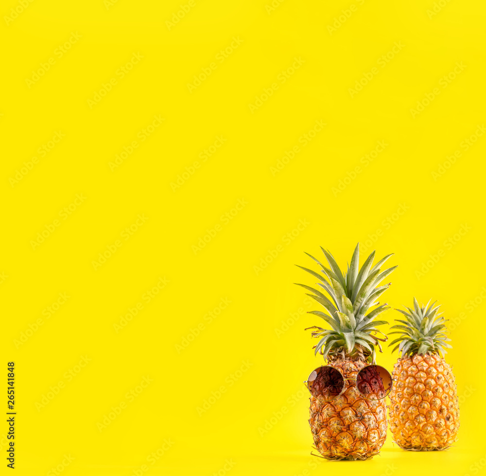 Creative pineapple looking up with sunglasses and shell isolated on yellow background, summer vacation beach idea design pattern, copy space close up