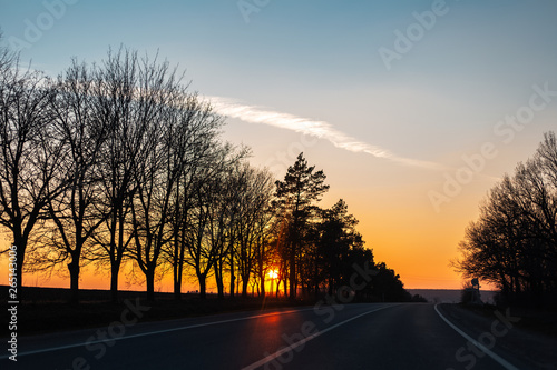 Landscape of unreal natural sunset on road from inside of car.