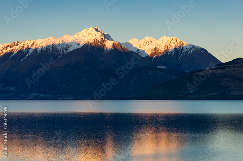 Snow-caped mountains and lake on sunset. Nature landscape
