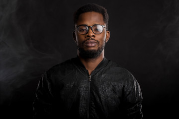 Portrait of handsome young African man on black background