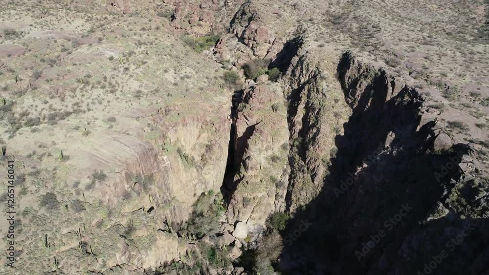 Aerial drone scene flying above canyon at dry, desertic red, landscape, detail of deep cliffs and waterfall. Hualco canyon at Rioja Province Argentina. Native monte vegetation Aerial drone scene flying above canyon at dry, desertic red, landscape, detail of deep cliffs and waterfall. Hualco canyon at Rioja Province Argentina. Native monte vegetation