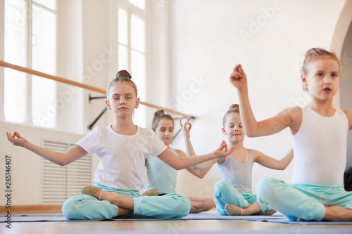 Group of children doing yoga sitting in lotus position with eyes closed, copy space