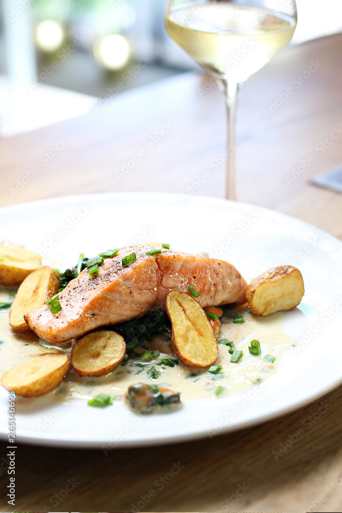 Salmon fillet with baked potatoes on a cream sauce with chives