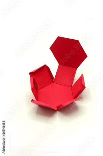 Geometric shape cut out of red paper and photographed on white background.Hexagonal prism. 2D shapefoldable to form a 3-dimensional shape or a solid.