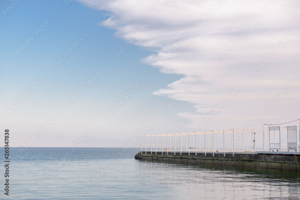 White sea pier and sky with clouds