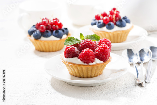 mini tarts with cream and berries on white table