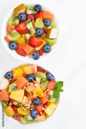 two bowls of fruit salad on white table, closeup top view
