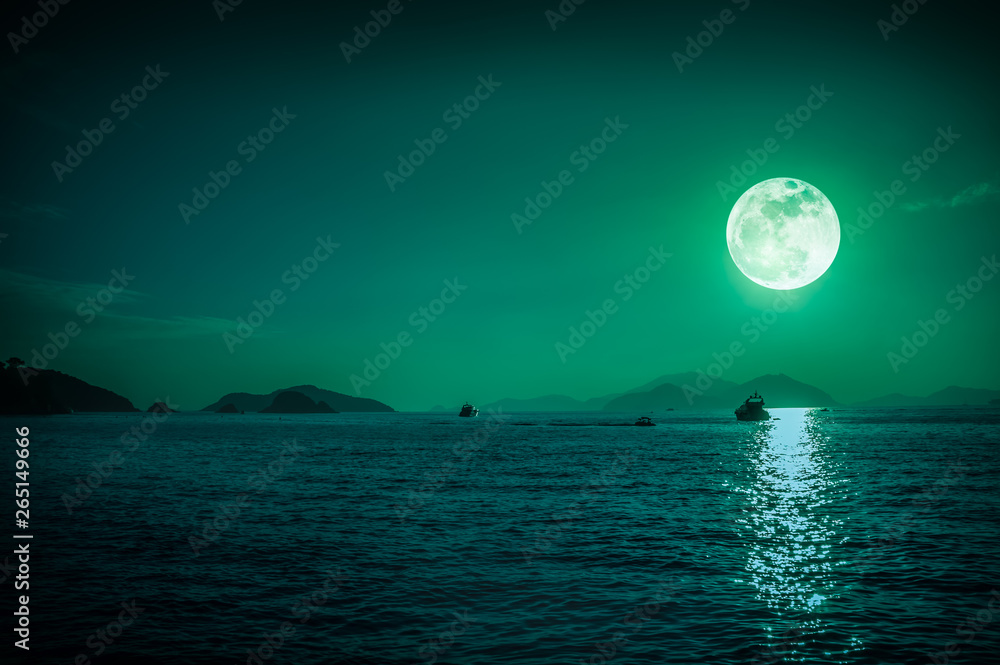 Scenic view of small boat in calm sea water at night time and super moon.