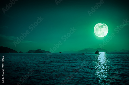 Scenic view of small boat in calm sea water at night time and super moon.