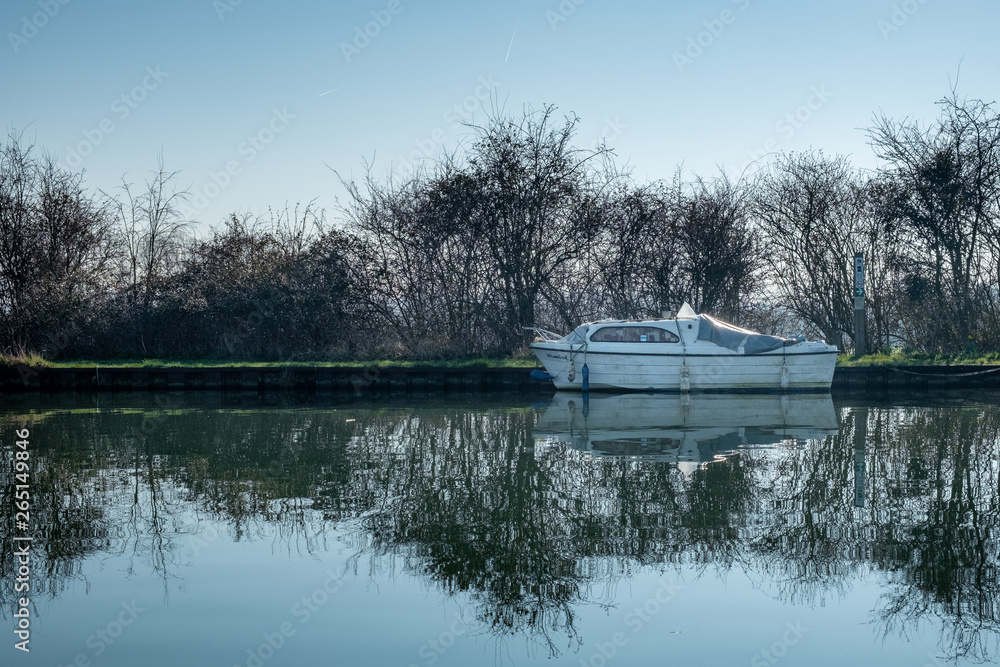 Obraz premium Boat on clear reflective canal on spring morning