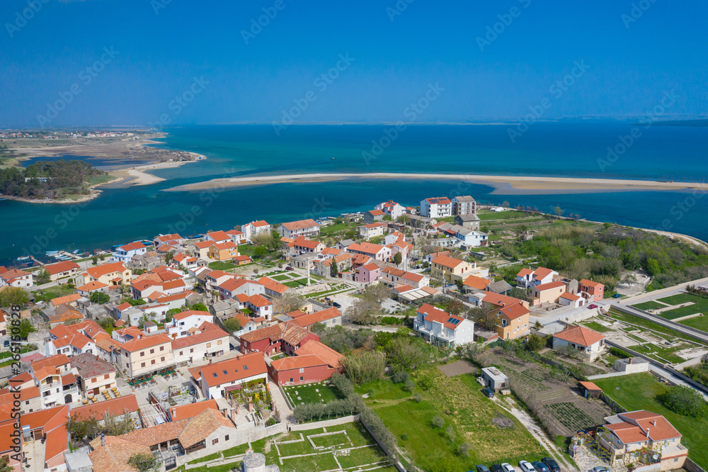 Aerial view of city of Nin. Summer time in Dalmatia region of Croatia. Coastline and turquoise water and blue sky with clouds. Photo made by drone from above.