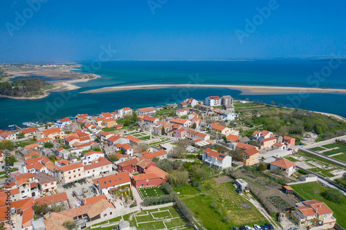 Aerial view of city of Nin. Summer time in Dalmatia region of Croatia. Coastline and turquoise water and blue sky with clouds. Photo made by drone from above.
