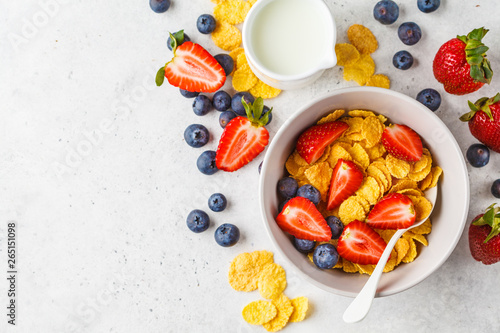 Photos Cornflakes with strawberries and blueberries in a bowl on white background, top view