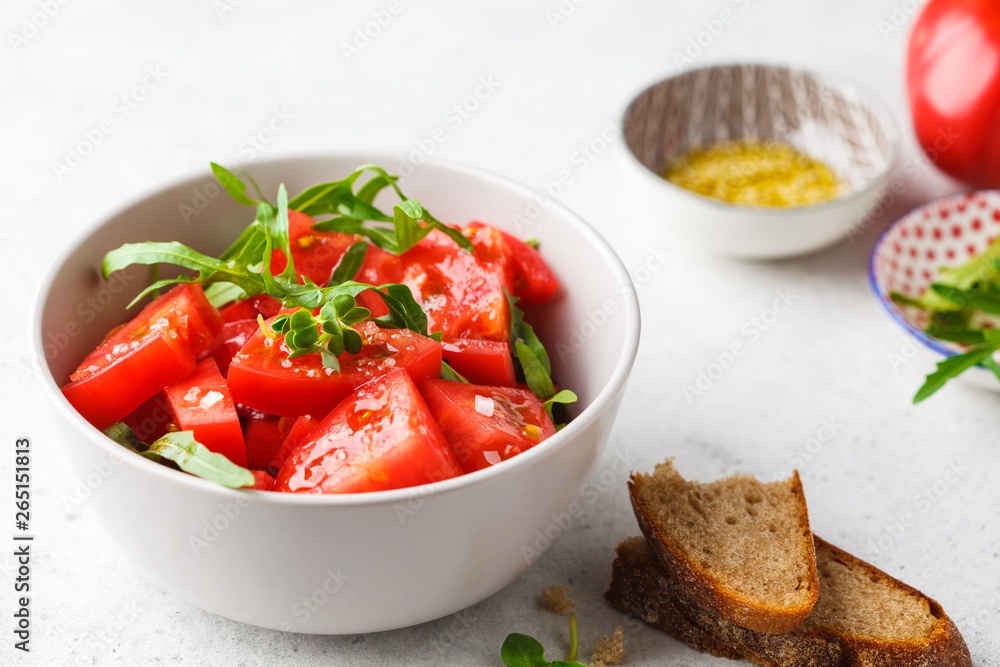 Tomatoes and arugula salad with sprouts and olive oil in gray bowl. Tomatoes and arugula salad with sprouts and olive oil in gray bowl.