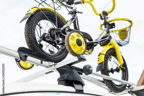 Bicycle transport - a children's bicycle on the roof of a car against the sky in a special mount for cycling. The decision to transport large loads and travel by car