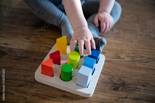 little hand of child playing with wooden blocks in diffrent colours. Closeup.