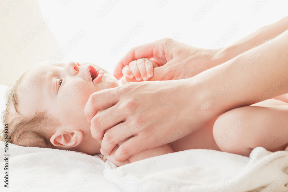 Baby and hands of a mother, indoors, blurred background Baby and hands of a mother, indoors, blurred background