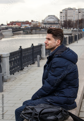 Sad young guy sitting by the river