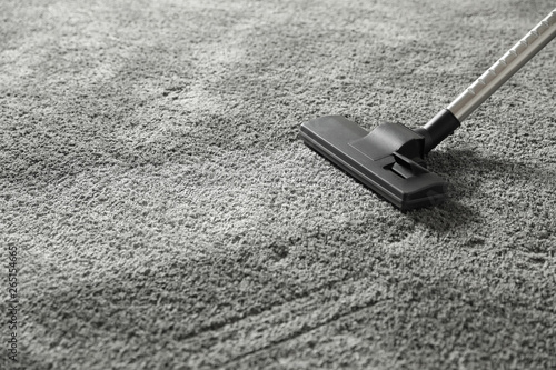 Removing dirt from grey carpet with vacuum cleaner. Space for text