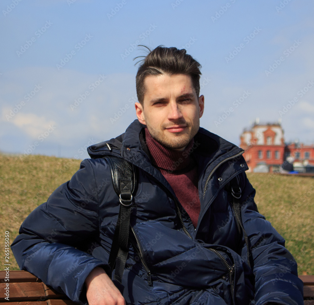 Obraz premium A young guy is sitting on a park bench