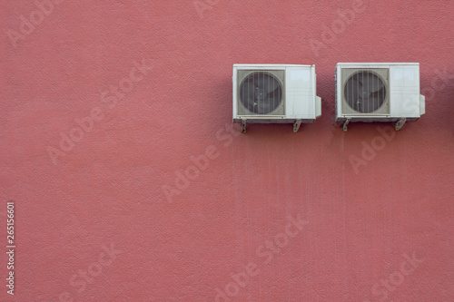 two white air conditioner radiators on a red granular concrete wall. rough surface texture © Pavel
