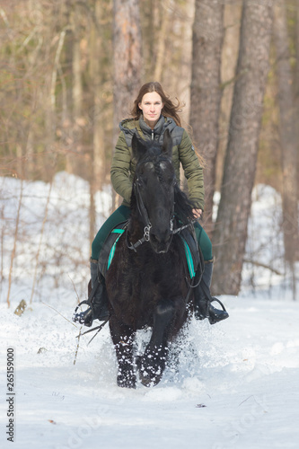 A woman with long hair riding a dark brown horse in the forest