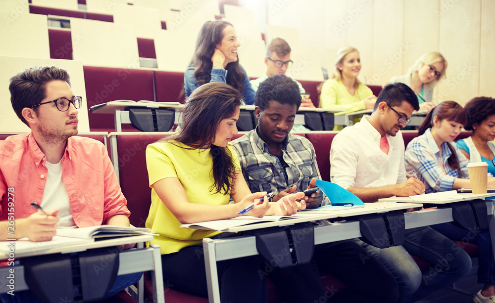 Obraz premium education, high school, university, learning and people concept - group of international students with smartphone at lecture