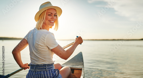 Smiling young woman canoeing on a lake in summer