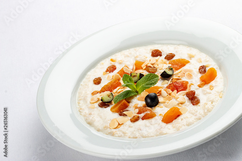 Oatmeal breakfast with raisins, dried apricots and peanuts on white background
