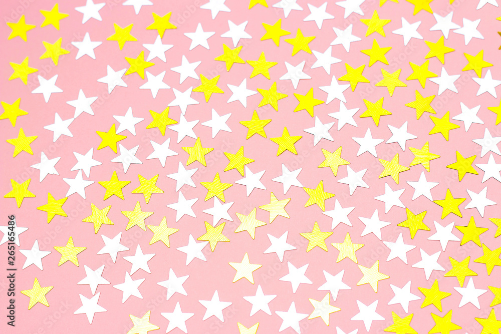 Golden stars of confetti on a white background, top view