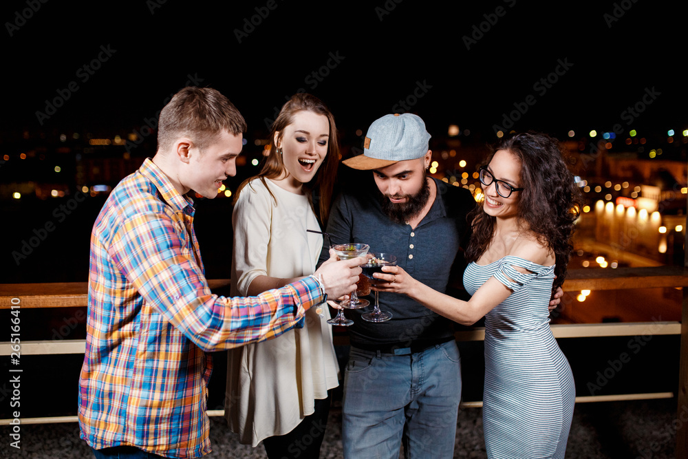 © Ilnur - friends with smiles on their faces in the bar have fun, drink cocktails, clink glasses.