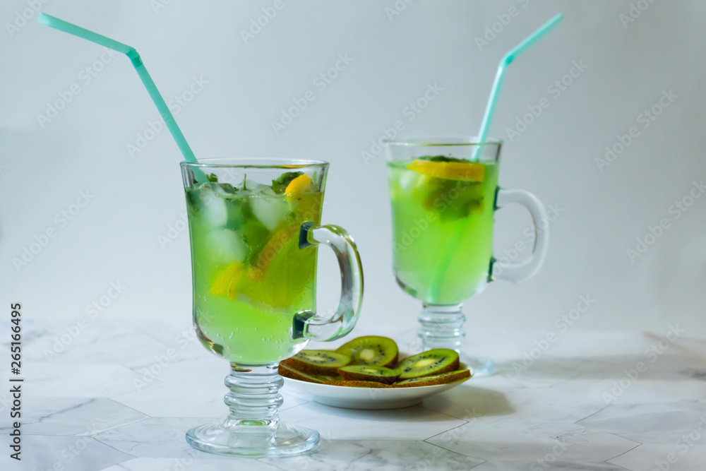 Refreshing lemonade from kiwi and lemon with ice on a light background. Horizontal orientation Refreshing lemonade from kiwi and lemon with ice on a light background. Horizontal orientation